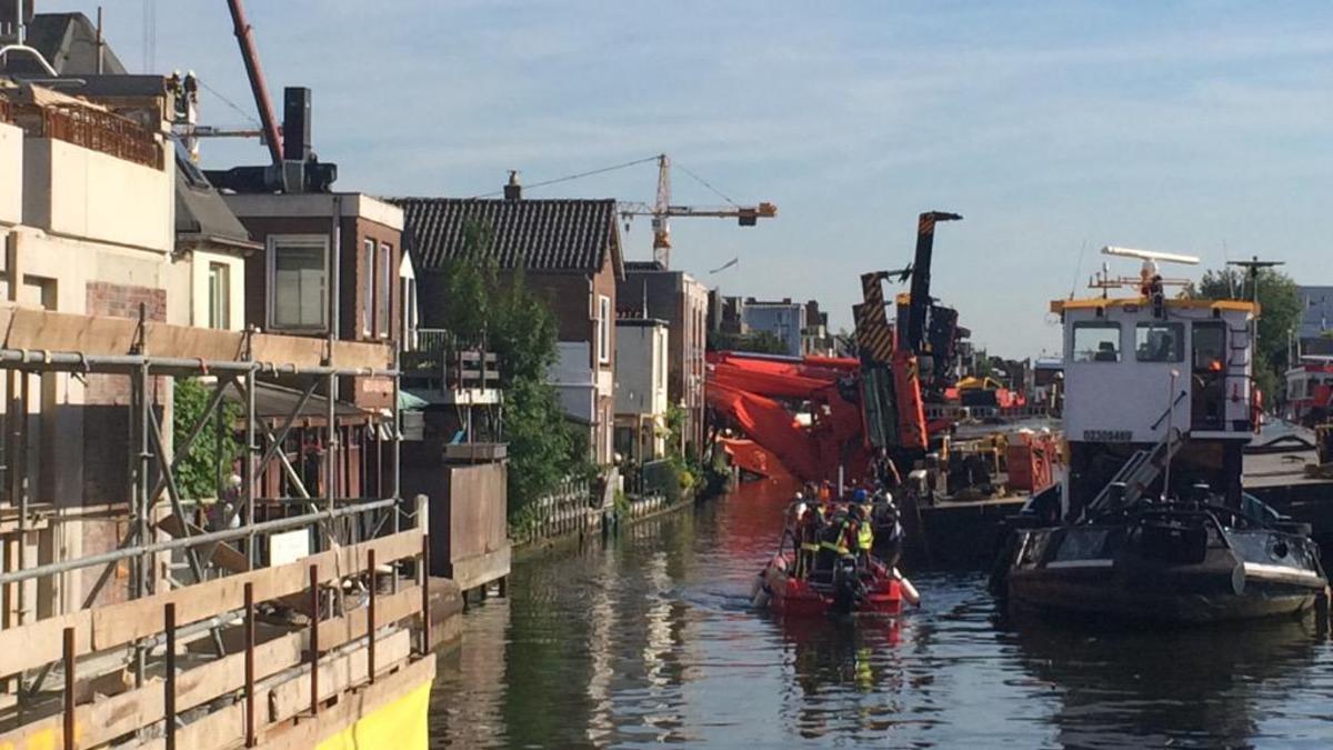 Kranen met brugdeel vallen op huizen