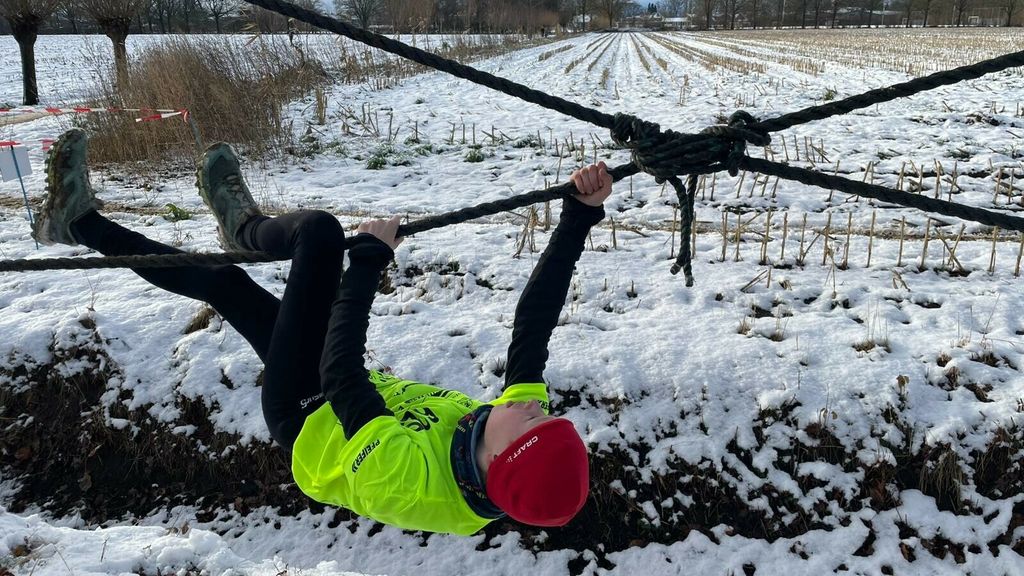 Kinderen rennen en klimmen door de sneeuw bij survivalrun