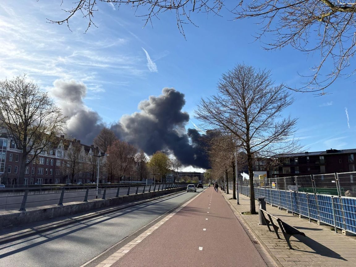 Grote rookwolk boven Amsterdam door brandende scooters